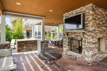 the outdoor living area has a stone fireplace and a television at Sovereign at Overland Park, Kansas